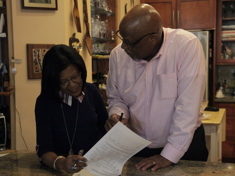 A couple stands at a kitchen counter while reviewing study materials.