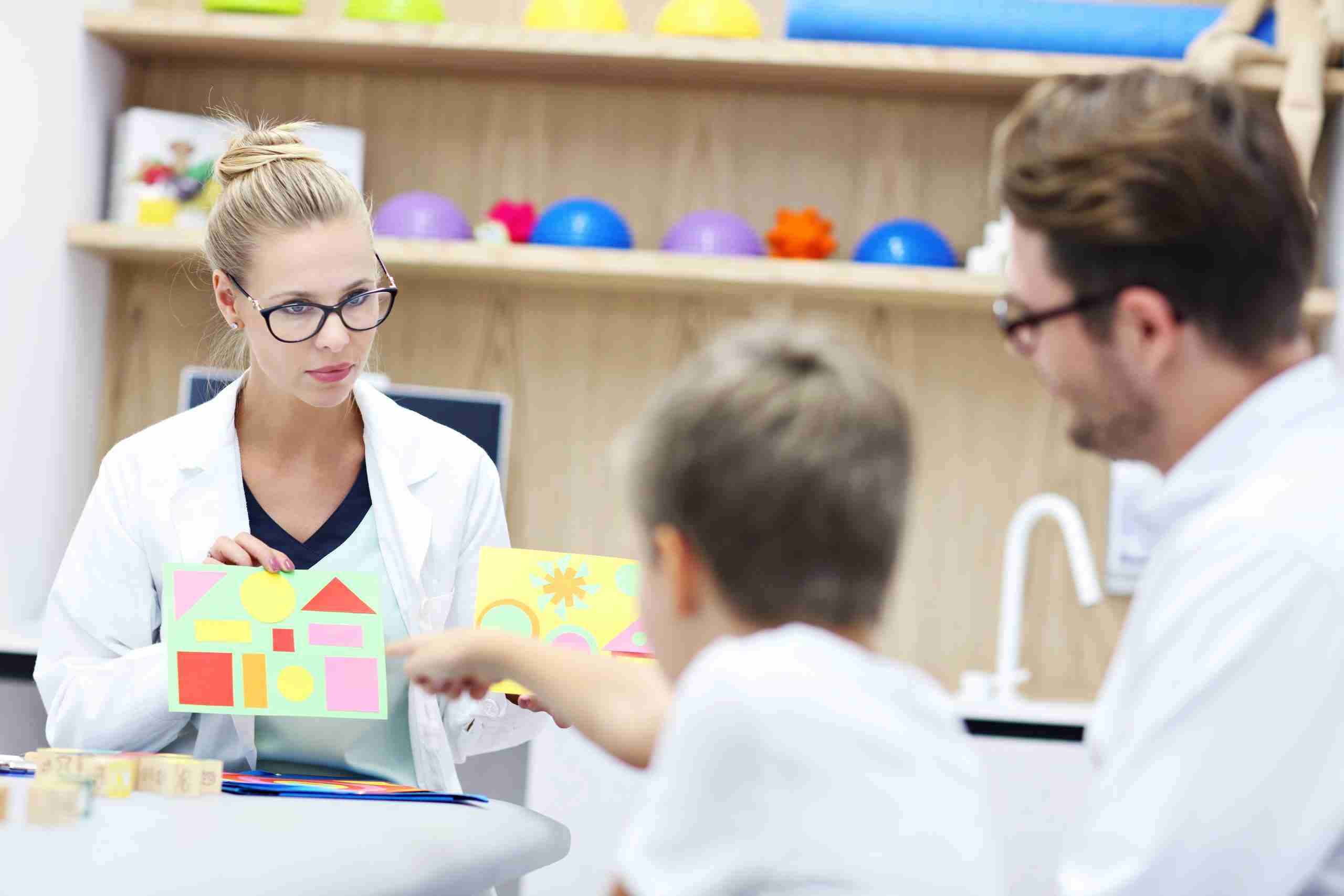A psychologist works with a father and son during a session to evaluate the child's development.